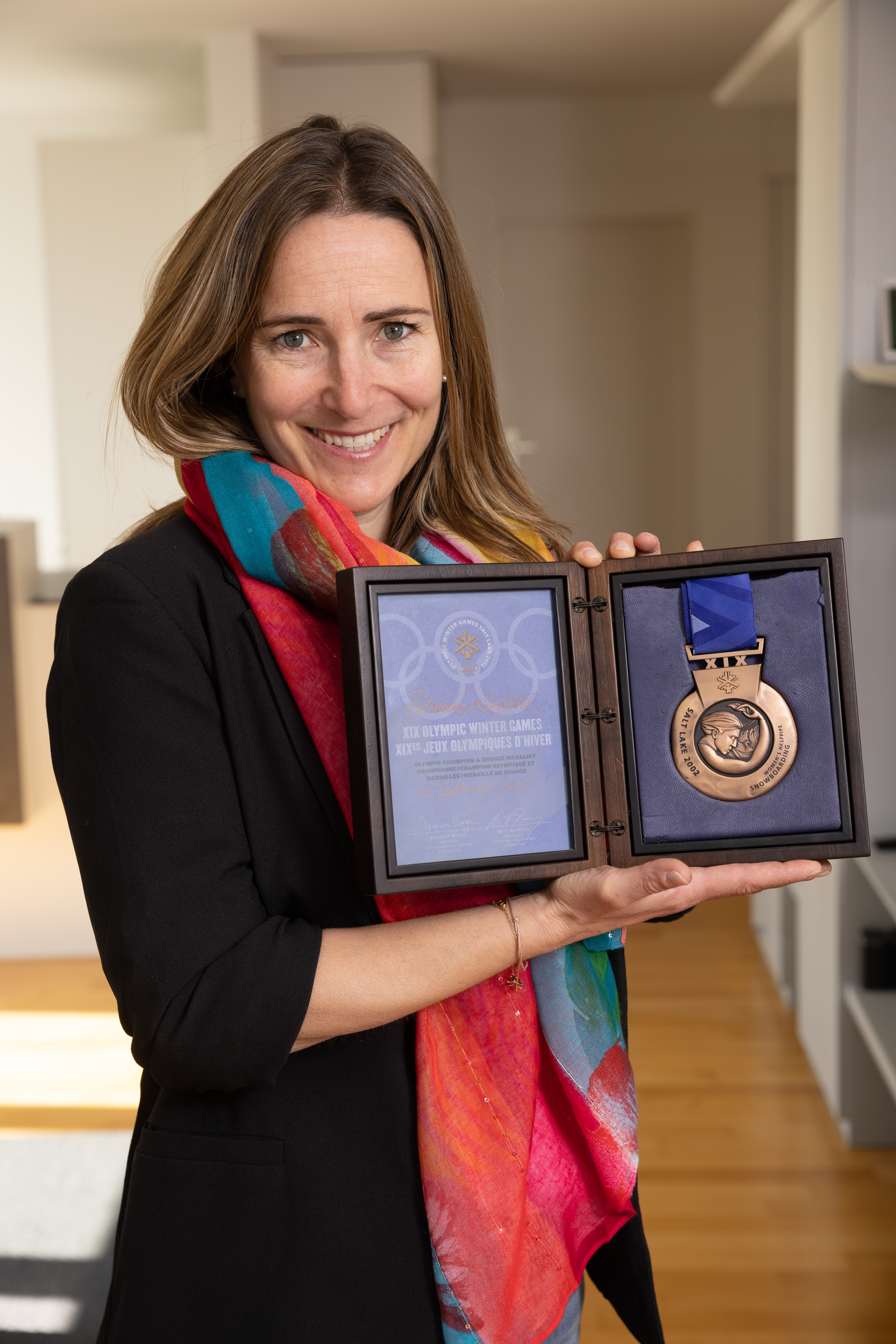 Junge Frau präsentiert stolz eine gewonnene Olympiamedaille.