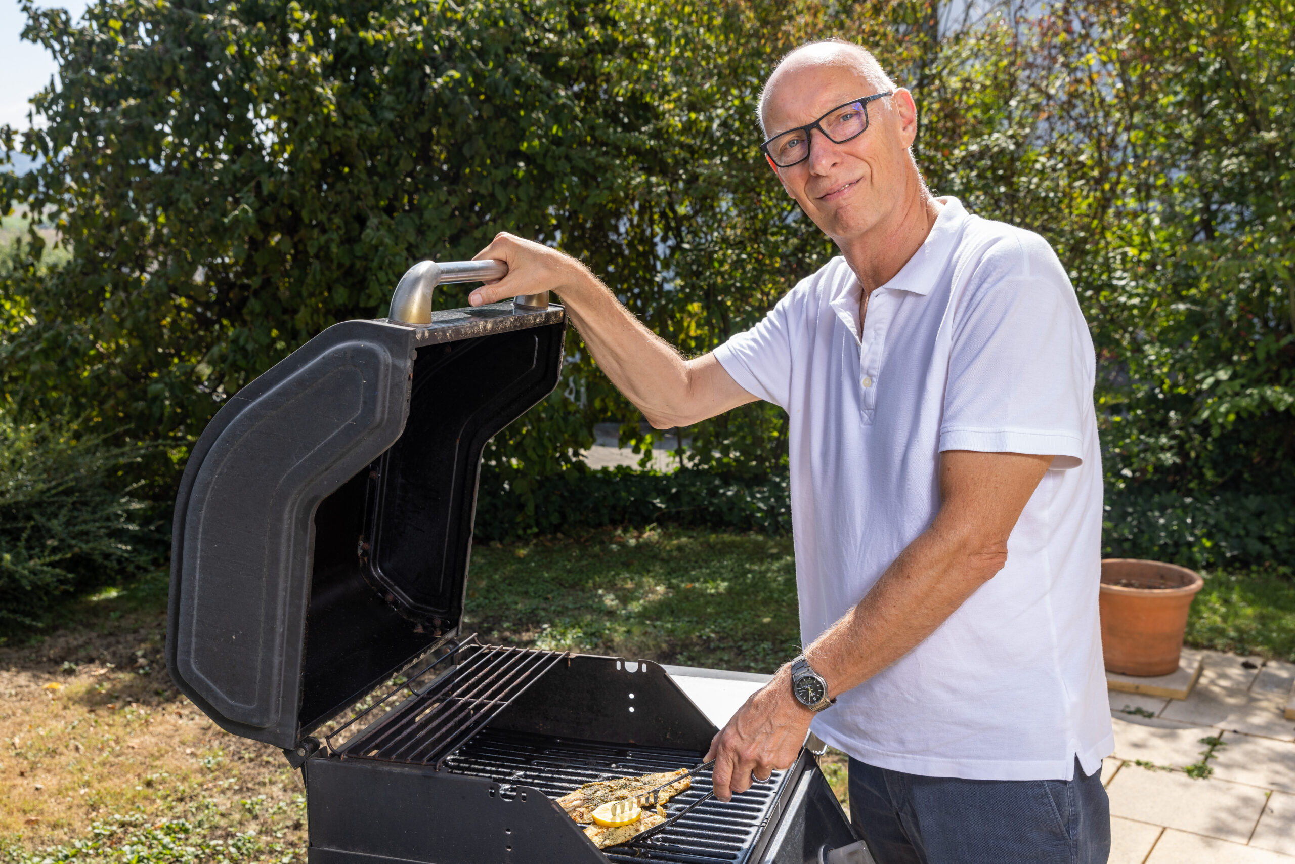 Rüstiger Senior am Grill im Garten